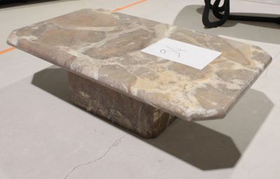 une table en pierre sur laquelle est posé un panneau, dans une pièce