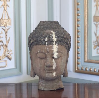 une statue représentant une tête posée sur une table devant un miroir