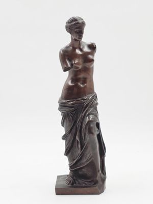 une statue antique en bronze représentant une femme debout sur un socle en marbre