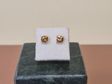 pair of gold stud earrings on a marble block on a table