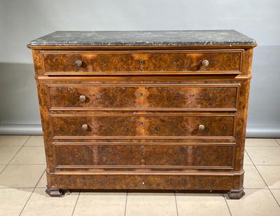 une commode ancienne avec un plateau en marbre, posée sur un sol carrelé
