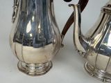 two silver teapots sitting next to each other on a table