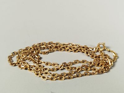 gros plan d'un bracelet en chaîne en or sur une surface blanche