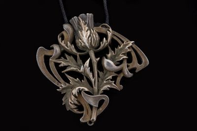 an image of a silver necklace with a thistle design on it