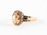 gros plan d'une bague en or avec une pierre rouge au centre
