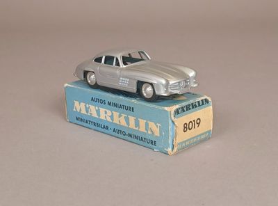 une petite voiture en argent posée sur une boîte