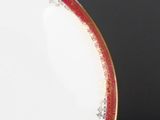 a white plate with a red border on a black table