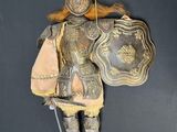 a statue of a man dressed in armor holding a shield and shield