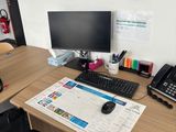 a desk with a computer, phone, and other office supplies on it