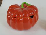 a red pumpkin shaped container with a green handle