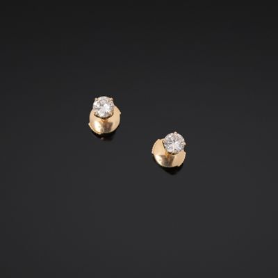 a pair of gold and diamond earrings on a black background