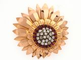 une image représentant une broche en forme de fleur, en or et diamants, sur fond blanc
