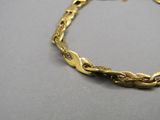 gros plan d'un bracelet en or sur une surface grise