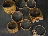 plusieurs bagues en or et une bague en argent posées sur un tissu noir