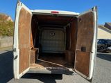 l'arrière d'une camionnette blanche dont la porte est ouverte, dans un parking