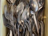a lot of silver spoons and forks in a box