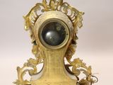 a gold clock with a black face on a white background