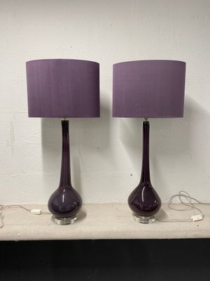 une paire de lampes de table en verre violet, avec des abat-jours violets, posées sur une étagère