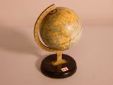 un petit globe terrestre posé sur un socle, sur une table