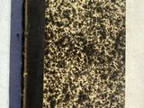un vieux livre posé sur une table à côté d'une feuille de papier