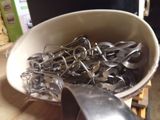 a white bowl filled with silver spoons on a wooden table