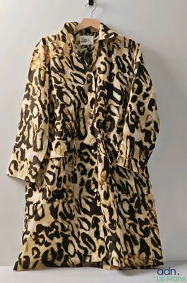 an animal print robe hangs on a hanger against a white wall