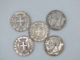 five different types of silver coins on a white surface