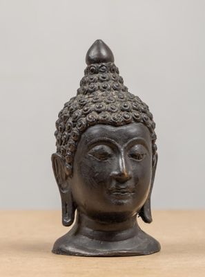 un gros plan sur une statue représentant une tête de Bouddha posée sur une table