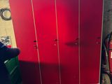 un homme debout à côté d'un casier rouge dans une pièce