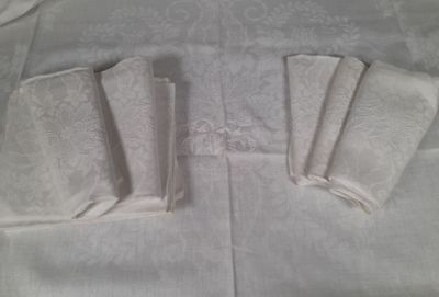 four folded napkins sitting on a white table cloth