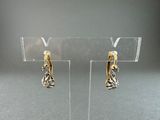 two tone gold and silver earrings on a clear display stand