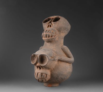 une vieille figurine en argile représentant un homme tenant un crâne