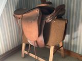a saddle on a stand in the corner of a room