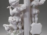 a white statue of angels with flowers on a pole