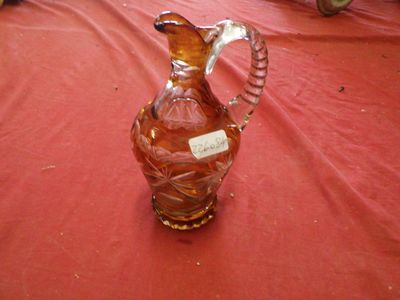 a glass pitcher on a red tablecloth with a label on it