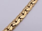a close up of a gold bracelet on a white surface