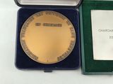 a gold medal sitting in a green box on a white table