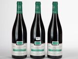 trois bouteilles de vin rouge sont posées côte à côte sur une surface blanche