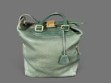 green leather handbag on grey background with gold hardware