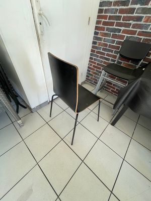 une chaise noire posée devant un mur de briques