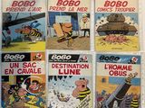 six comic books of various sizes and colors on a white surface