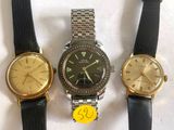 three watches are sitting on a white surface with a yellow tag