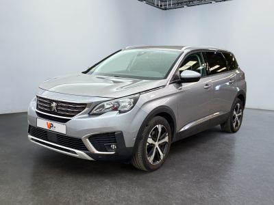 La voiture argentée est garée dans une grande pièce au sol noir.