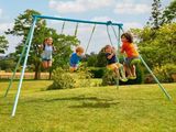 three children playing on a swing set in a yard