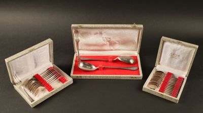 trois cuillères en argent et une cuillère en argent dans une boîte posée sur une table