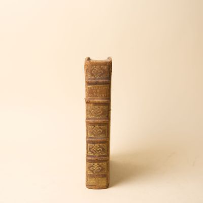 un vieux livre posé sur une table à côté d'un mur blanc