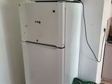 a white refrigerator with a microwave on top of it