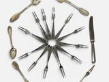 plusieurs fourchettes et cuillères disposées en cercle sur une surface blanche