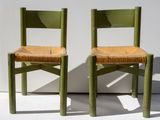two green chairs sitting next to each other on a white surface