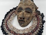 un gros plan d'un masque accroché à un collier orné de perles